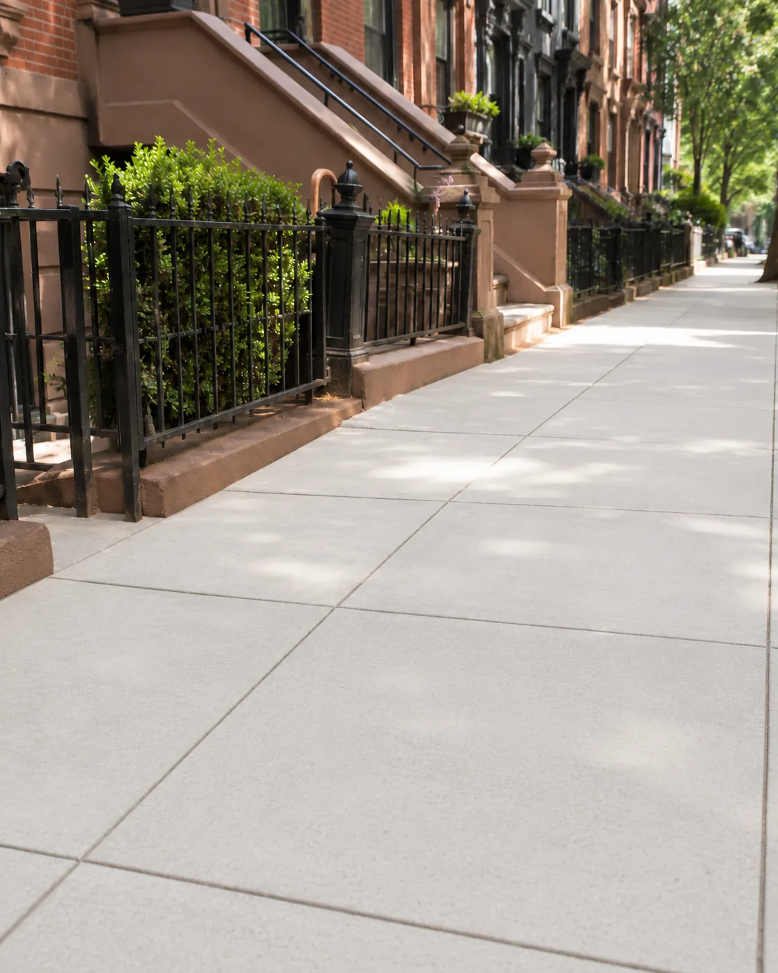 Newly repaired concrete sidewalk outside NYC brownstone properties after replacement