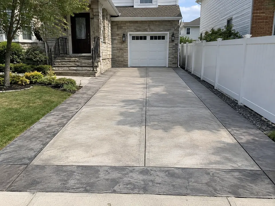 Finished residential concrete driveway with control joints and landscaped borders.