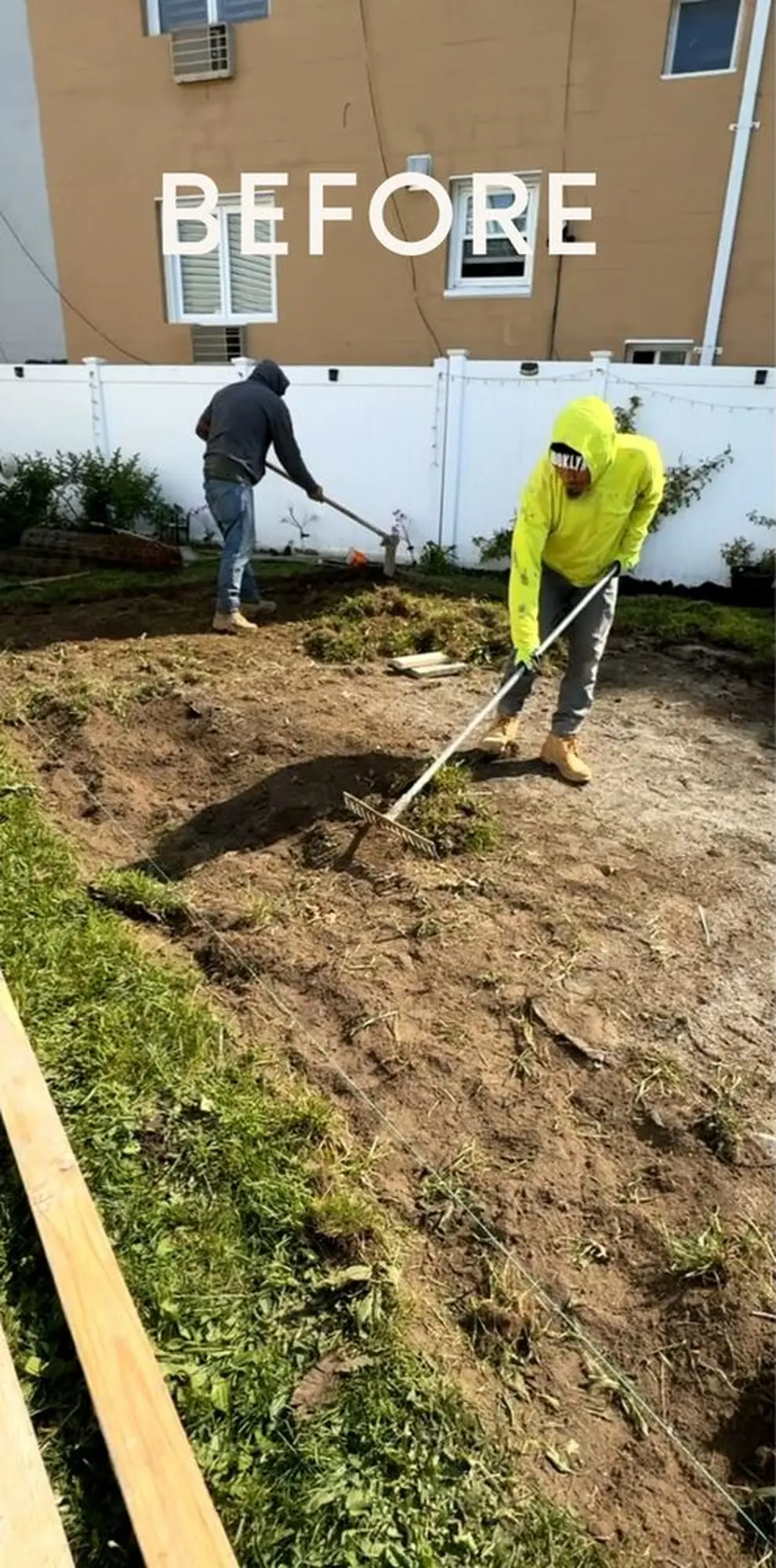 Workers leveling and preparing an excavated residential outdoor area for concrete installation.