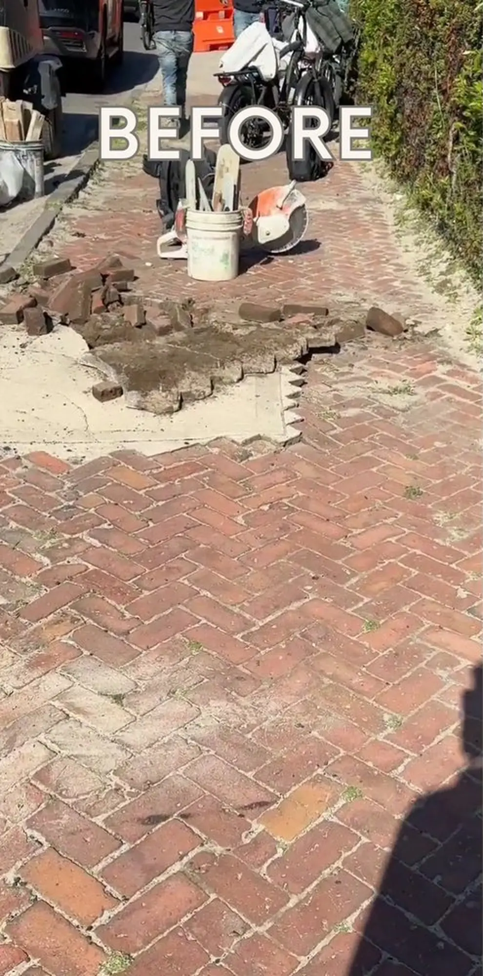 Damaged brick-paved outdoor surface with missing bricks and broken sections exposing the underlying ground.