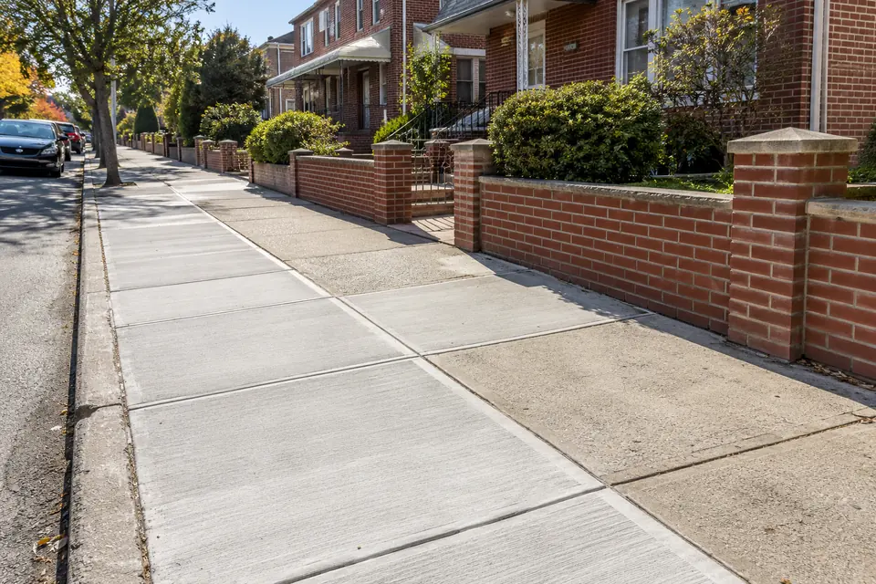 Newly replaced concrete sidewalk sections along an NYC residential street