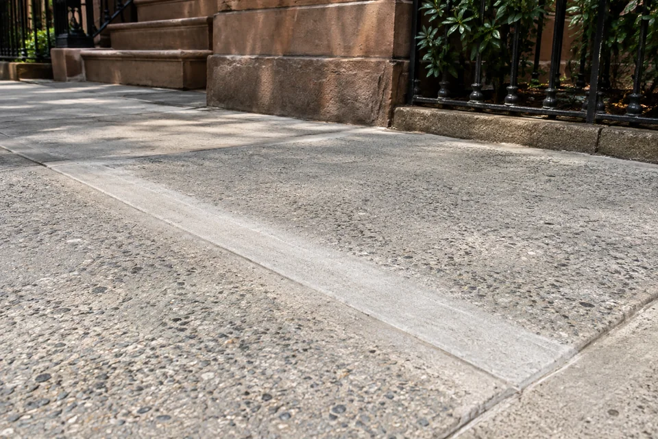 Repaired uneven concrete sidewalk section after trip hazard correction in NYC
