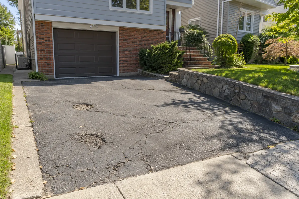 Cracked and deteriorated driveway surface before repair at an NYC property